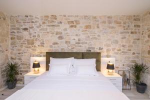 a bedroom with a large white bed with two lamps at Studio Apartman REA in Trogir