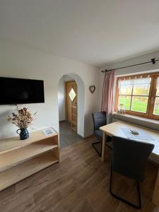 ein Wohnzimmer mit einem Schreibtisch und einem Tisch in der Unterkunft Apartment Rothenlehen in Bischofswiesen