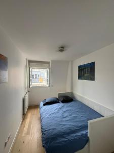 1 dormitorio con 1 cama azul en una habitación blanca en Appartement moderne et agréable, idéalement placé pour JO 2024, en Puteaux