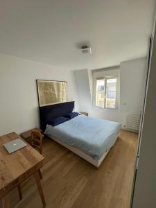 1 dormitorio con cama y mesa con ordenador portátil en Appartement moderne et agréable, idéalement placé pour JO 2024, en Puteaux