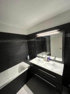 a bathroom with a sink and a tub and a mirror at Appartement moderne et agréable, idéalement placé pour JO 2024 in Puteaux