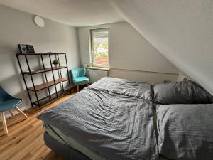 a bedroom with a bed and a chair and a window at NEU! Canossablick Bad Harzburg Inklusive Bettwäsche in Bad Harzburg