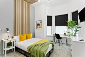 una camera da letto con letto con cuscini gialli e scrivania di Nottingham Group Stay - 8 x Studio Apartments, sleeps 16, Free Parking a Nottingham