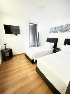 a hotel room with two beds and a flat screen tv at Hotel Portal de los Andes in Bogotá