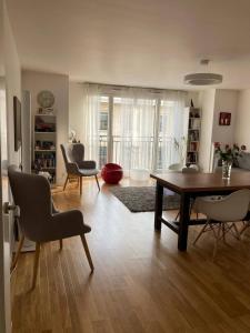 ein Wohnzimmer mit einem Esstisch und Stühlen in der Unterkunft Chaleureux et lumineux appartement in Puteaux