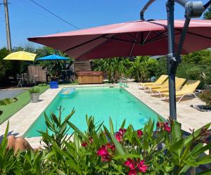 einen Pool mit Sonnenschirm und einigen Stühlen in der Unterkunft JOLIE MAISON CONTEMPORAINE St Emilion in Néac