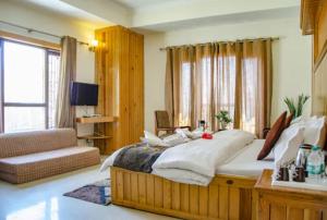 um quarto grande com uma cama grande e um sofá em Hotel Abhinandan Mussoorie Near Mall Road - Parking Facilities & Prime Location - Best Hotel in Mussoorie em Mussoorie