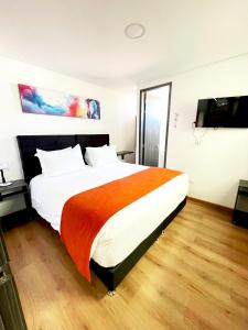 a bedroom with a large bed with an orange blanket at Hotel Portal de los Andes in Bogotá