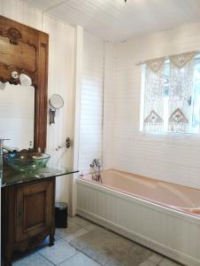 baño con bañera, lavabo y ventana en Au nid d'hirondelles, en Selles