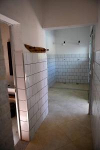 pusta łazienka z białymi ścianami wyłożonymi kafelkami i drzwiami w obiekcie Sítio agradável com piscina em Condomínio fechado w mieście Brumadinho