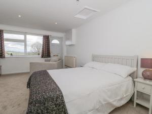 ein Schlafzimmer mit einem großen weißen Bett und einem Fenster in der Unterkunft 27 Fernhill Heights in Bridport