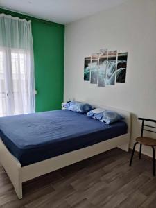 a bedroom with a blue bed with a green wall at Olivia Studios - Melina's home near the sea in Agia Triada