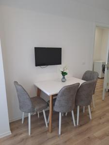 a dining room table with chairs and a tv on a wall at Erdis Home Nr 1 in Tirana