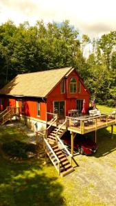 ein rotes Haus mit einer Terrasse und einem Dock in der Unterkunft WhiSki Cabin *12-acres with mountain views!* in Chester