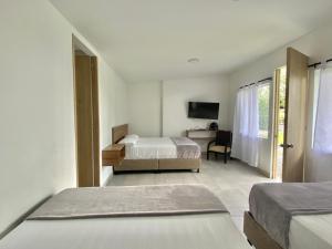 1 dormitorio con 2 camas, escritorio y TV en ORIGEN FINCA HOTEL, en Quimbaya