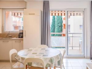 eine weiße Küche mit einem Tisch und einem Balkon in der Unterkunft Appartement Bormes-les-Mimosas, 2 pièces, 4 personnes - FR-1-610-99 in Bormes-les-Mimosas