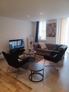 een woonkamer met een bank en stoelen en een televisie bij Q Flat Skyview Central Bradford in Bradford