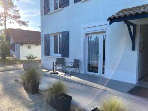 une maison blanche avec 2 chaises et une terrasse dans l'établissement Logis Hôtel Emeraude des Bois, à Mimizan-Plage