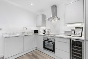 uma cozinha branca com armários brancos e um lavatório em Spacious 1 Bedroom Apartment in Central Newbury em Newbury