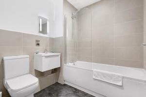 a white bathroom with a toilet and a bath tub at Spacious 1 Bedroom Apartment in Central Newbury in Newbury