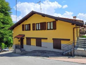 Casa amarilla con ventanas con persianas marrones en MansardHouse zona Bellagio, en Magreglio