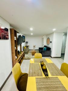sala de estar con mesa y sillas amarillas en Magnifico y confortable apartamento amoblado # 303, en Bogotá