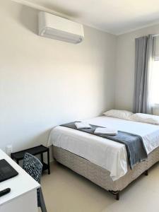 a bedroom with a bed and a desk with a laptop at Flat Canoa Quebrada in Aracati