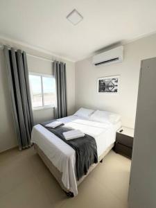 a bedroom with a large white bed with a window at Flat Canoa Quebrada com terraço in Aracati