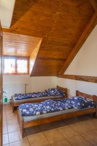 two beds in a room with a wooden ceiling at mlyn-osvracin in Osvračín