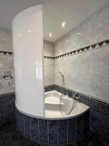 a white bath tub in a bathroom with tiled walls at Villa Garden Island in Berlin