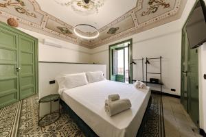 1 dormitorio con 1 cama blanca grande y toallas. en Palazzo Villelmi, en Cefalú