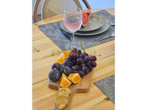 a glass of wine and some fruit on a cutting board at Glycine Jasmim in Castro Marim