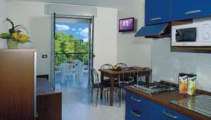 eine Küche mit blauen Schränken, einem Tisch und einem Esszimmer in der Unterkunft Comfortable apartment with terrace - Beahost in Bibione