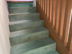 a stairway with green steps and a wooden railing at Luxury Village Attic and Suite in my Shared Home in Tiana