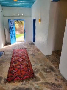 ein Zimmer mit einem Teppich auf dem Boden mit einer Tür in der Unterkunft منزل حجري بحديقتين in Hajlah