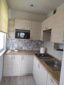 une cuisine avec des armoires blanches, un évier et une cuisinière dans l'établissement Studio Niebieskie, à Wałbrzych