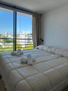 ein großes weißes Bett in einem Zimmer mit einem großen Fenster in der Unterkunft nardos suites in Balcarce