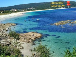 a group of people swimming in the water on a beach at Casa Velay in Fisterra +3 photos
