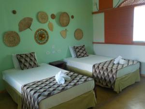 duas camas num quarto com paredes verdes em POUSADA LUATOUR Praia Pontal do Coruripe em Coruripe