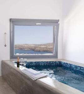 uma casa de banho com uma grande banheira e uma grande janela. em Pancratium Villas & Suites em Akrotírion