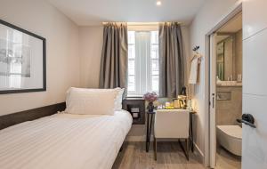 a bedroom with a bed and a desk and a sink at King's Cross Express Inn in London