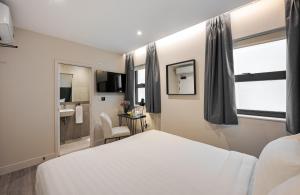 een slaapkamer met een wit bed en een badkamer bij King's Cross Express Inn in Londen