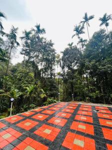 an orange and black tiled floor with palm trees in the background at Forest Bliss Malnad in Kalasa