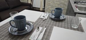 una mesa con dos tazas de café y cubiertos en APPARTAMENTO CHIATAMONE 26 en Nápoles