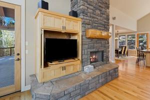 a stone fireplace in a living room with a tv at Lucy Lou 30 Day Minimum home in Bend