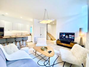 a living room with white furniture and a kitchen at Velvet - By BEST KEYS - Maison Duplex Élégante - Plein Centre Ville - Déco Minimaliste & Cosy - Literie Haut de Gamme - 2 chambres séparées - Lit Queen Size & 1 canapé convertible - Smart TV - Machine à Café Nespresso - WiFi Fibre - Check-in Autonome in Sens