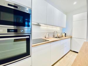 a kitchen with white cabinets and a stainless steel appliance at Velvet - By BEST KEYS - Maison Duplex Élégante - Plein Centre Ville - Déco Minimaliste & Cosy - Literie Haut de Gamme - 2 chambres séparées - Lit Queen Size & 1 canapé convertible - Smart TV - Machine à Café Nespresso - WiFi Fibre - Check-in Autonome in Sens +8 photos