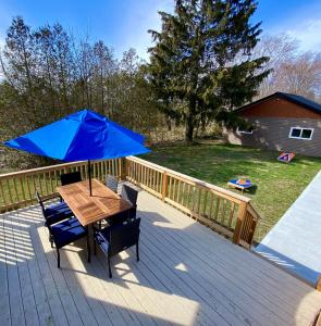 a table with a blue umbrella on a deck at Creekside Cottage - kayak/SUP, fishing, game room in Kingsville