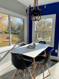 a dining room with a white table and chairs and two windows at Creekside Cottage - kayak/SUP, fishing, game room in Kingsville