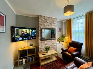 a living room with a couch and a tv on a brick fireplace at Waterloo House - Urban Oasis Townhouse in Nottingham